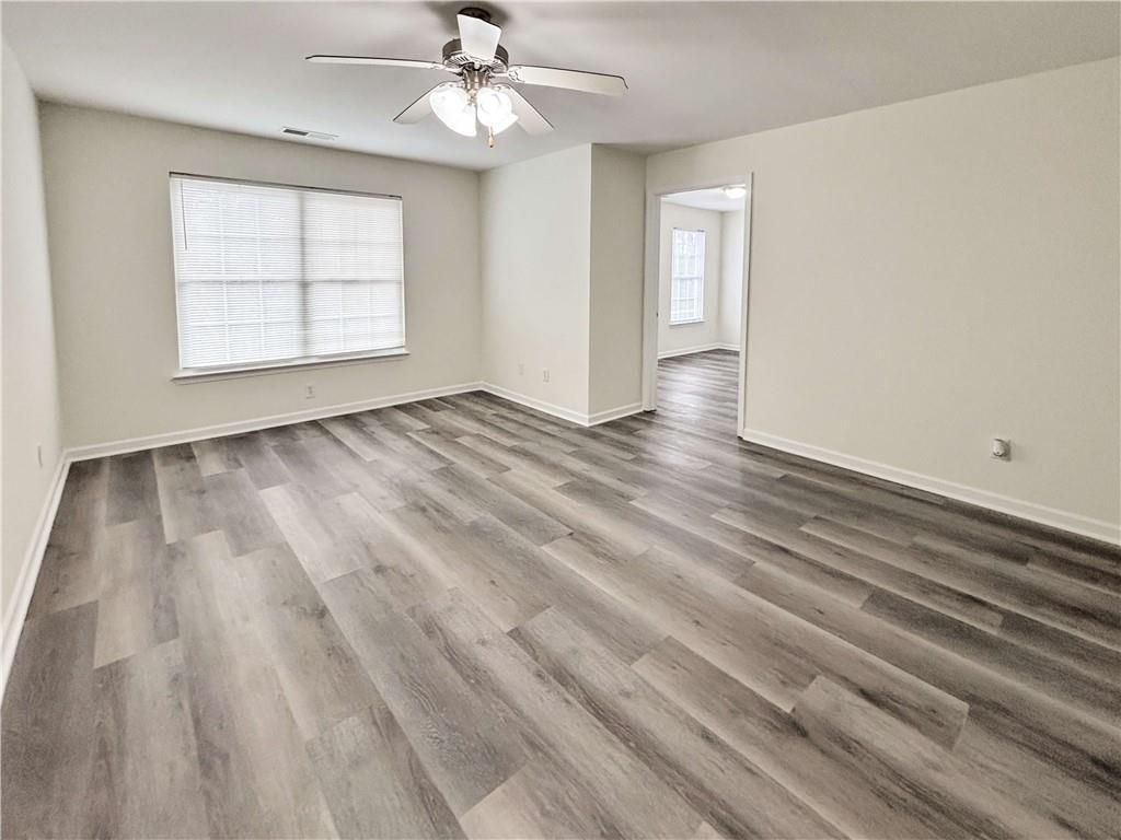 1400 Stonehaven Circle, Unit 1406 Cartersville, GA 30121 - Photo 4 of 21 an empty room with wooden floor chandelier fan and windows