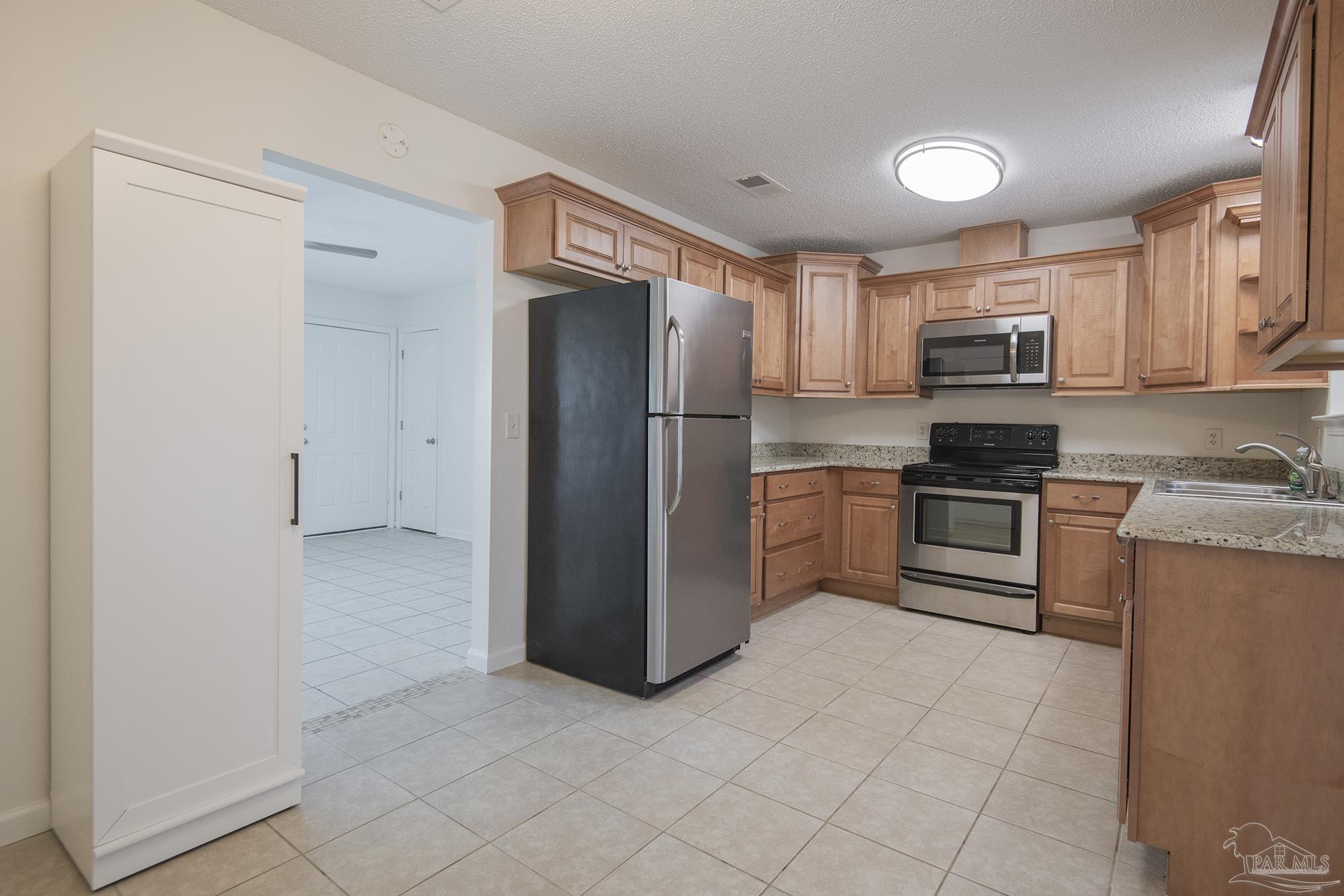 5578 Cyanamid Road Milton, FL 32583 - Photo 15 of 33 a kitchen with granite countertop a refrigerator and a stove top oven