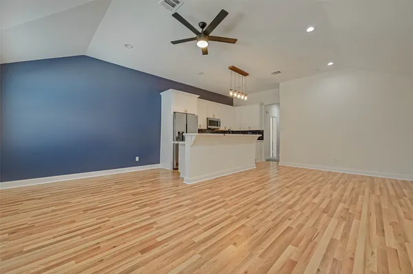 a large white kitchen with kitchen island white cabinets and stainless steel appliances