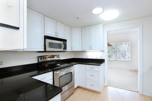 a kitchen with granite countertop white cabinets and black appliances