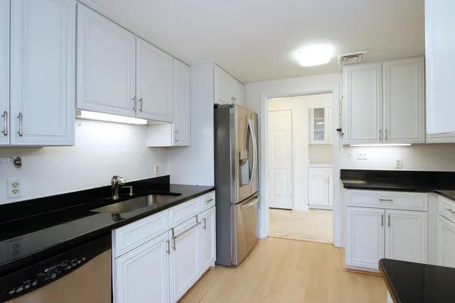 a kitchen with granite countertop white cabinets and stainless steel appliances
