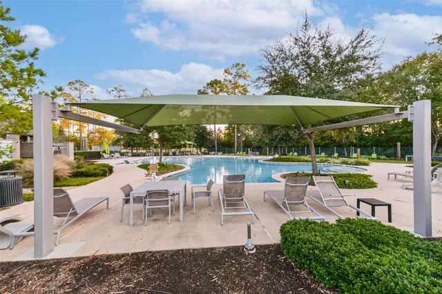 a view of a patio with lawn chairs under an umbrella with large trees