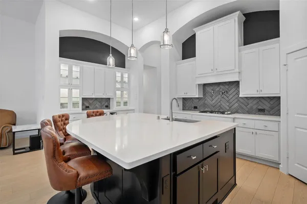 a kitchen with stainless steel appliances granite countertop a sink a stove and white cabinets with wooden floor