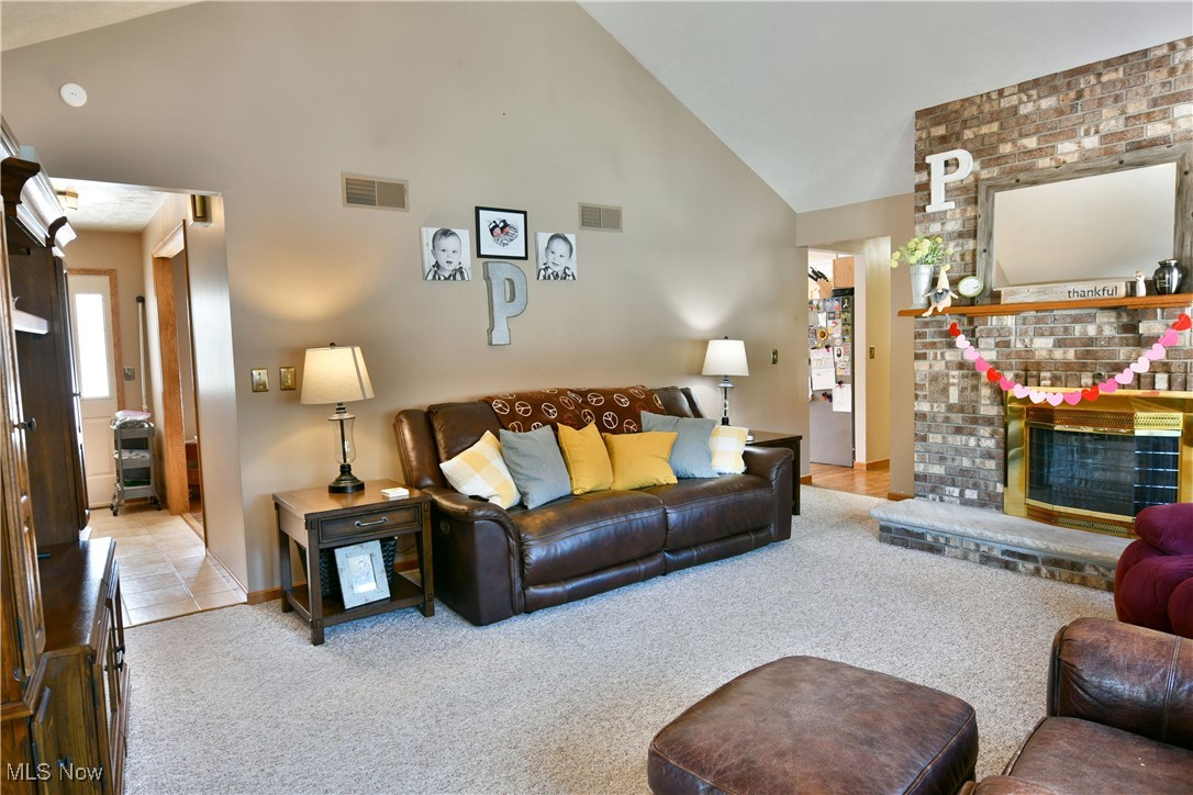 5915 Downs Road Northwest Warren, OH 44481 - Photo 21 of 50 Carpeted living room with a brick fireplace and high vaulted ceiling