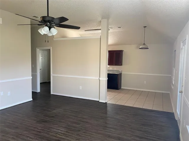 a view of empty room with wooden floor and ceiling fan