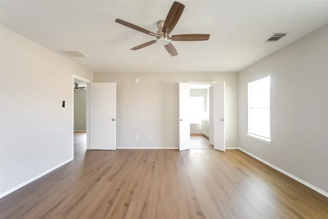 a view of empty room with wooden floor and fan