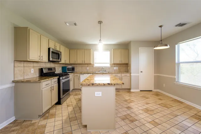 a kitchen with stainless steel appliances granite countertop a stove a sink and a refrigerator