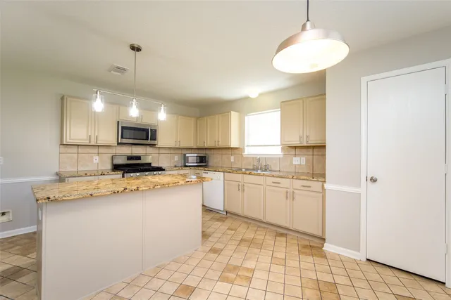 a kitchen with stainless steel appliances granite countertop a sink a stove a refrigerator a microwave oven with white cabinets