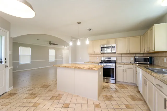 a kitchen with stainless steel appliances granite countertop a stove top oven a sink dishwasher and a refrigerator