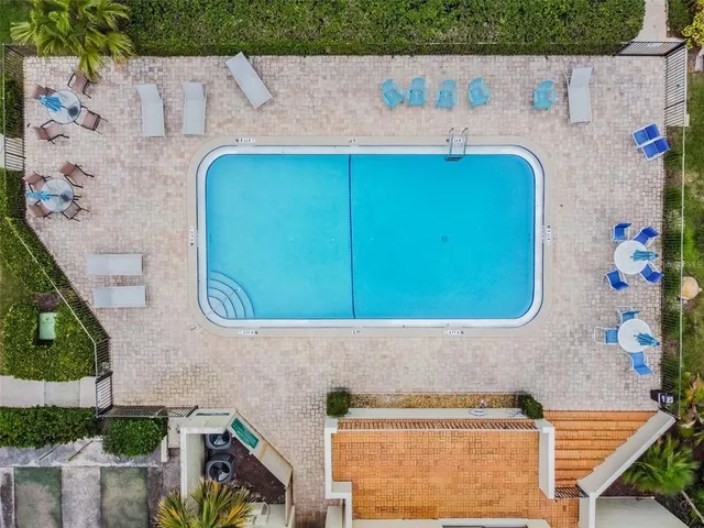 a sign that is sitting in front of a house with a large tree