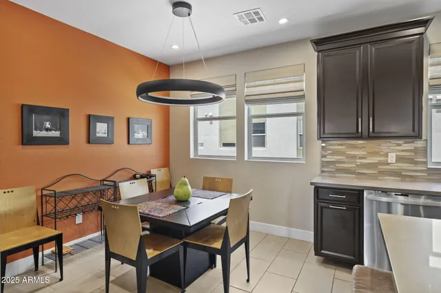 a kitchen with stainless steel appliances granite countertop a dining table chairs and a refrigerator