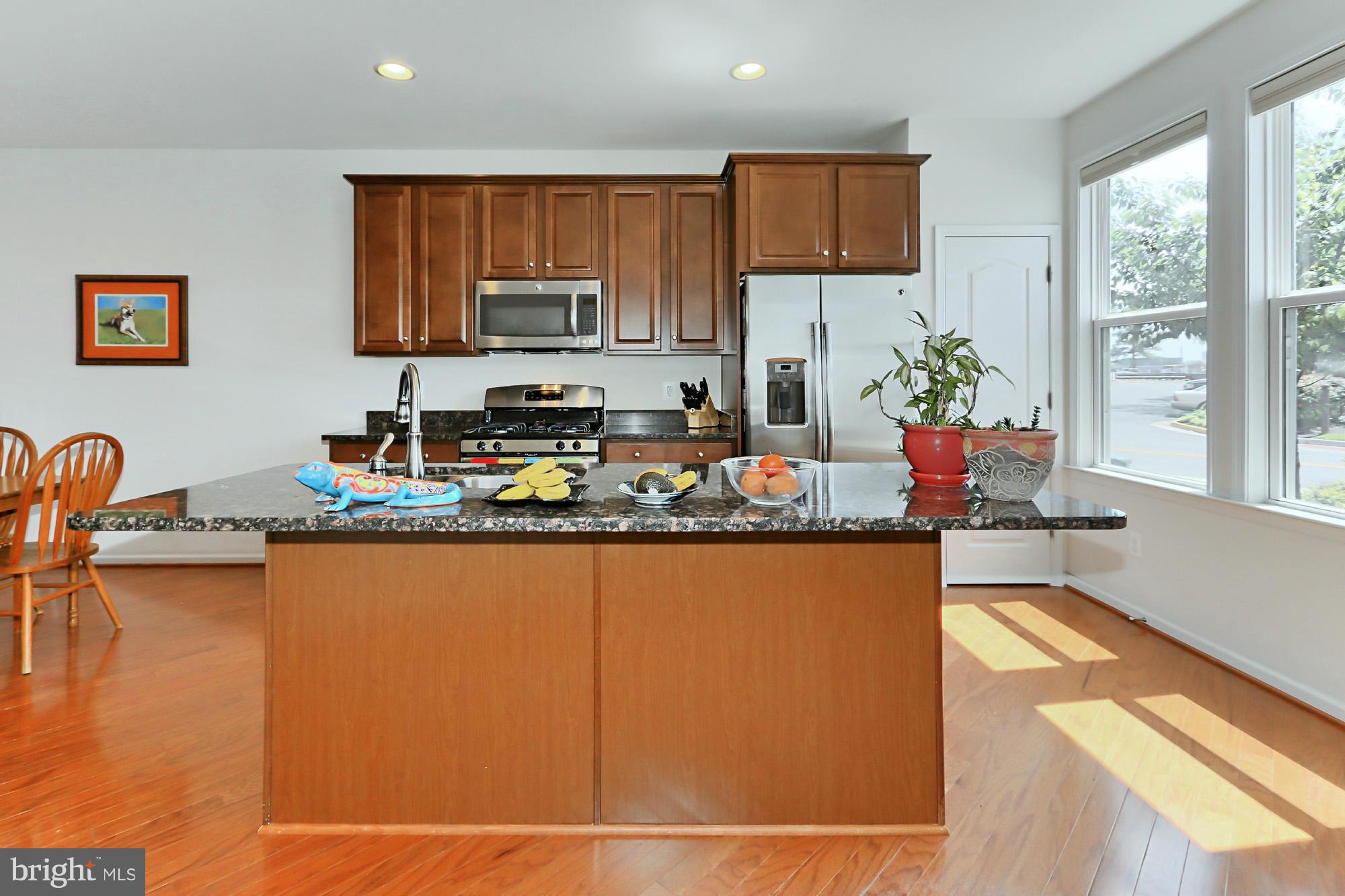 9419 Zebedee Street Manassas, VA 20110 - Photo 13 of 30 a kitchen with granite countertop a stove a sink a refrigerator and a dining table with wooden floor