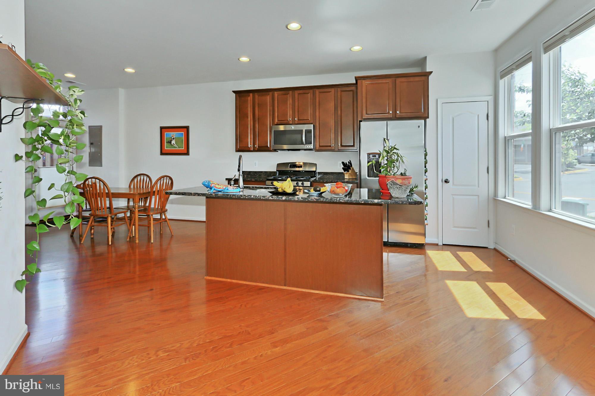 9419 Zebedee Street Manassas, VA 20110 - Photo 10 of 30 a kitchen with stainless steel appliances granite countertop a stove top oven a sink dishwasher and a dining table with garden view