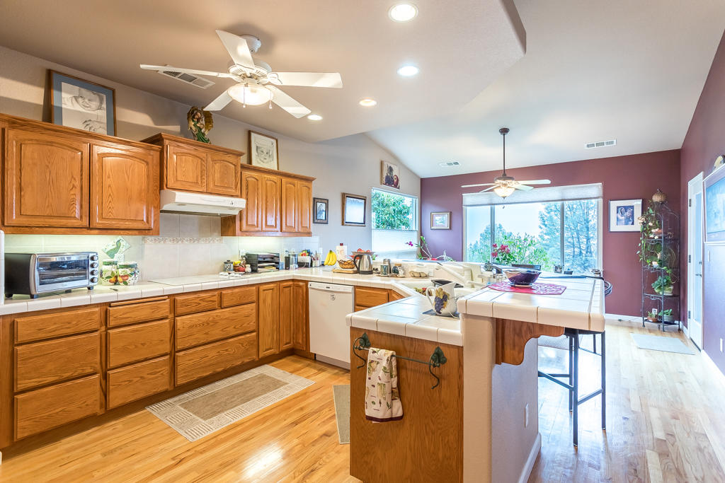 1575 Barbara Road Redding, CA 96003 - Photo 6 of 27 a kitchen with stainless steel appliances kitchen island granite countertop a stove a sink a refrigerator and white cabinets with wooden floor