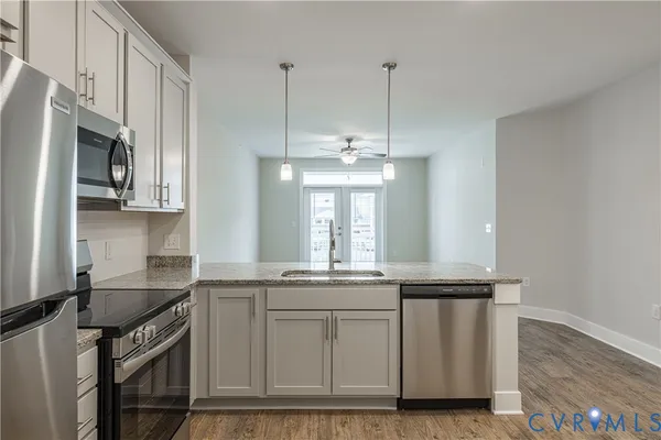 a kitchen with stainless steel appliances granite countertop a sink a stove a refrigerator and island with wooden floor