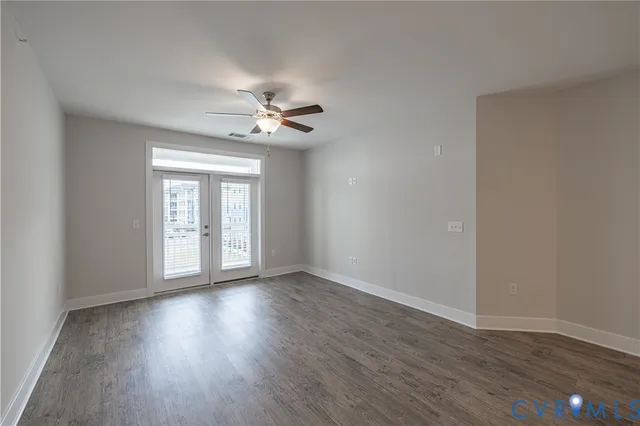 a view of an empty room with a window and wooden floor