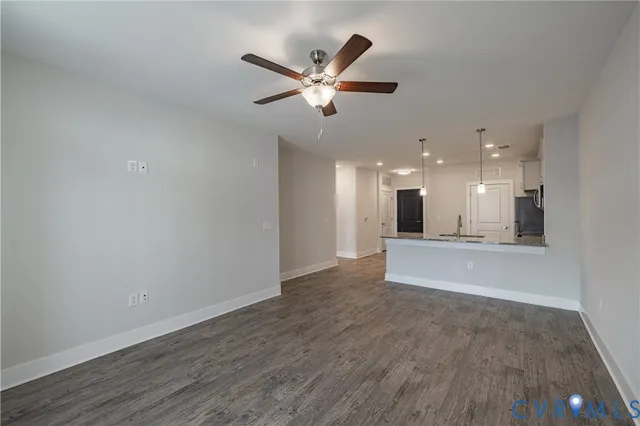 a view of an empty room with wooden floor and a ceiling fan