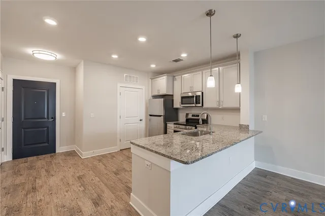 a kitchen with kitchen island granite countertop wooden cabinets a refrigerator and a sink