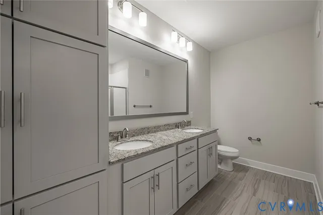 a bathroom with a granite countertop sink toilet and mirror