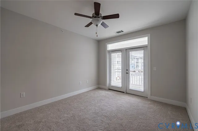 an empty room with a ceiling fan and window