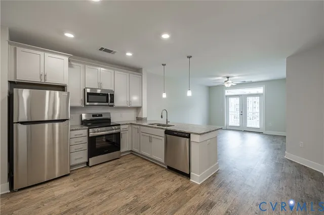 a kitchen with kitchen island granite countertop appliances cabinets wooden floor and a window