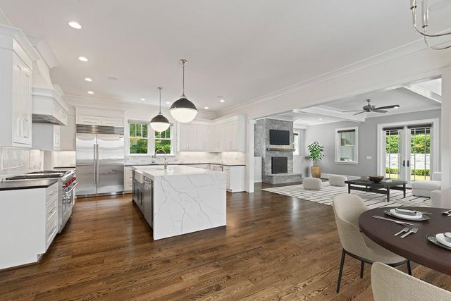 a kitchen with stainless steel appliances granite countertop a stove top oven a sink dishwasher a dining table and chairs with wooden floor