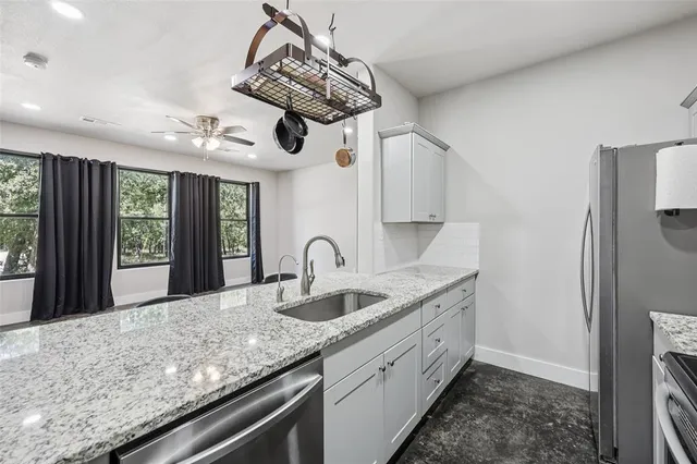a kitchen with stainless steel appliances granite countertop a sink a refrigerator and window
