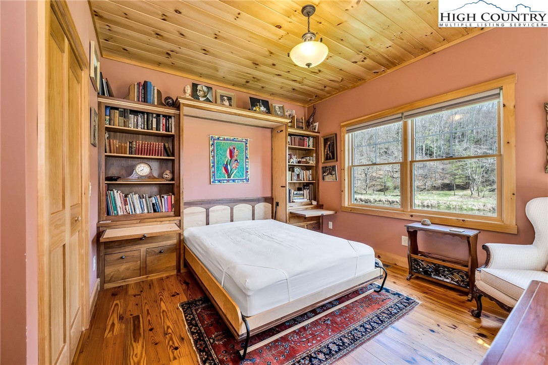 1976 Hartzog Ford Road West Jefferson, NC 28694 - Photo 12 of 50 a bedroom with a bed bookshelf and a large window