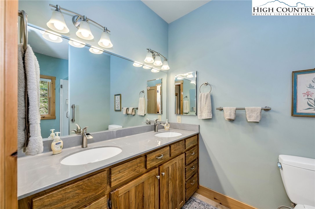 1976 Hartzog Ford Road West Jefferson, NC 28694 - Photo 18 of 50 a bathroom with a granite countertop sink a toilet and a large mirror