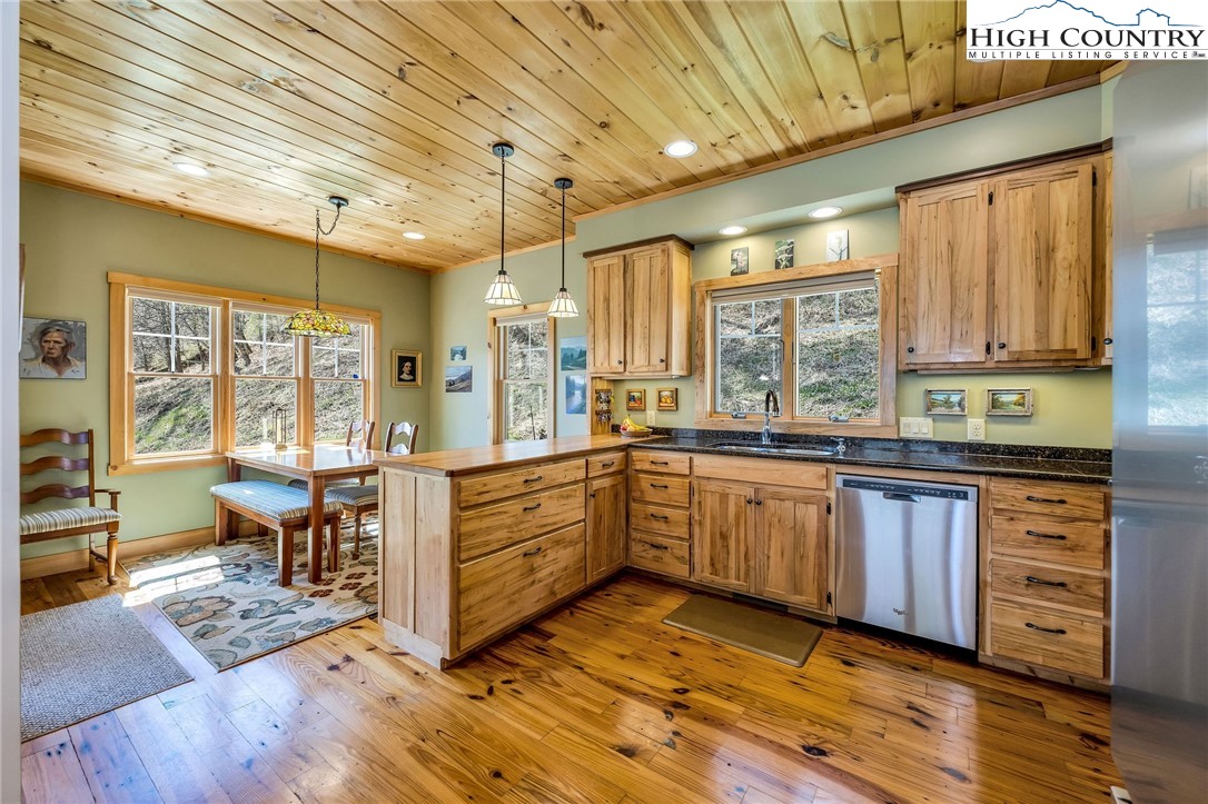 1976 Hartzog Ford Road West Jefferson, NC 28694 - Photo 28 of 50 a kitchen with stainless steel appliances kitchen island granite countertop a stove a sink and white cabinets with wooden floor