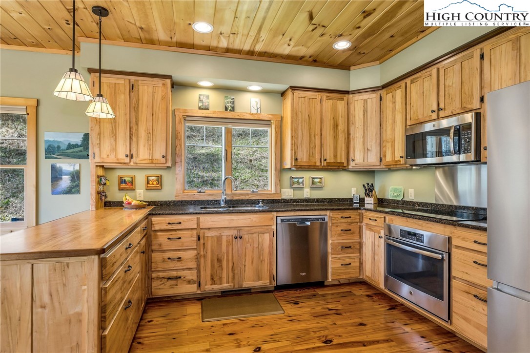 1976 Hartzog Ford Road West Jefferson, NC 28694 - Photo 29 of 50 a kitchen with stainless steel appliances granite countertop a stove a sink and a refrigerator