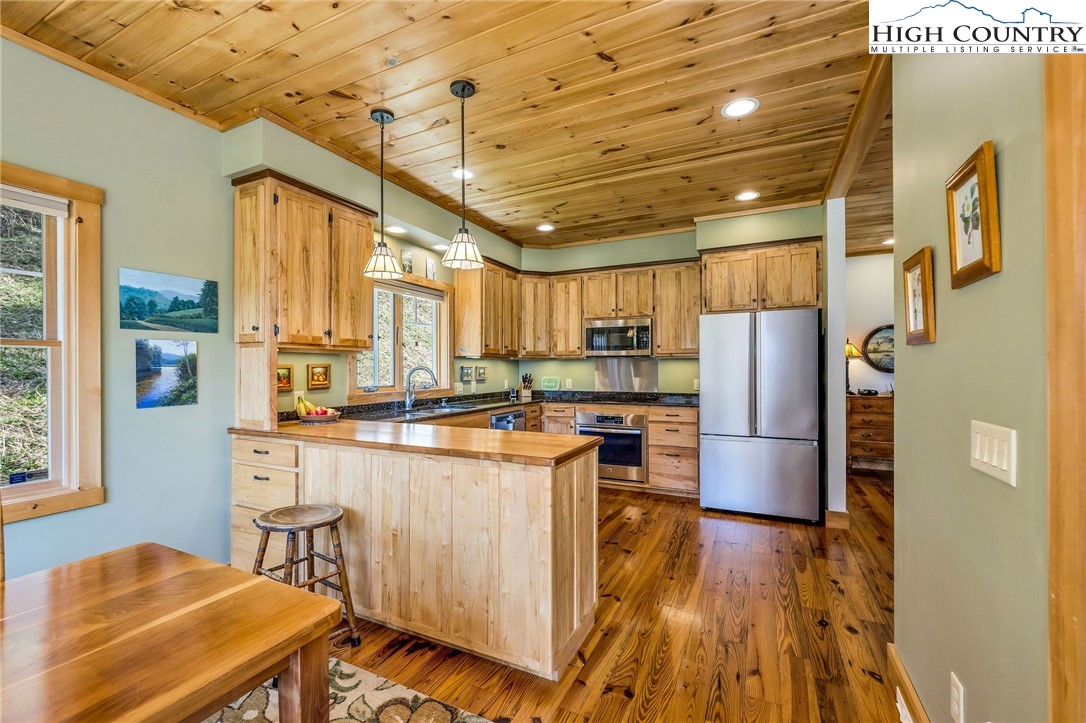 1976 Hartzog Ford Road West Jefferson, NC 28694 - Photo 32 of 50 a kitchen with stainless steel appliances a refrigerator a stove a sink dishwasher and wooden cabinets with wooden floor