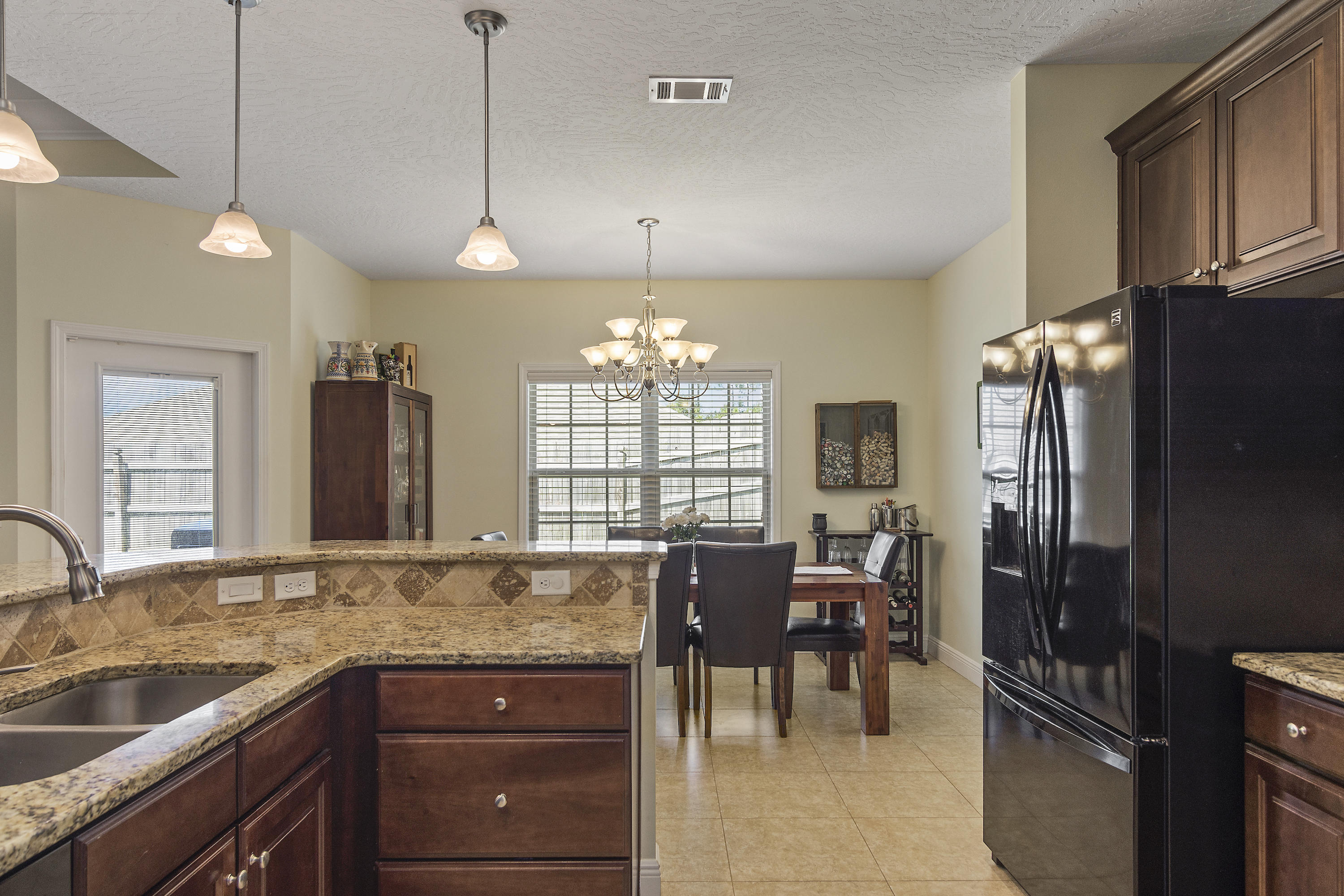 4605 Hermosa Road Crestview, FL 32539 - Photo 22 of 46 a large kitchen with granite countertop a sink counter space dining table and stainless steel appliances