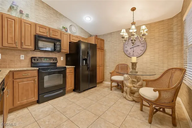 a kitchen with stainless steel appliances granite countertop a sink a stove a refrigerator cabinets and chairs