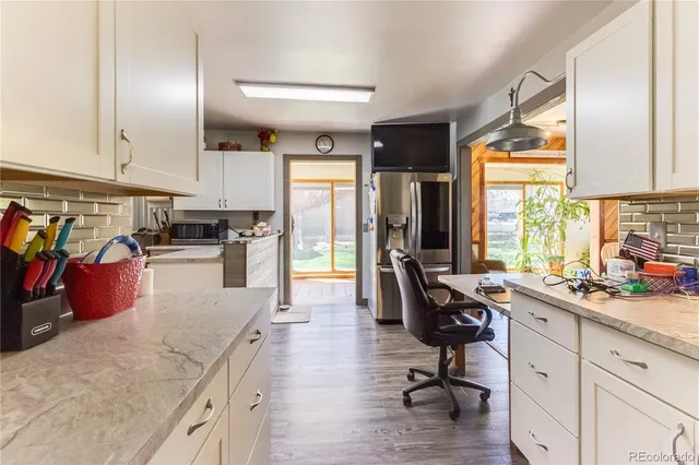 a kitchen with stainless steel appliances kitchen island granite countertop a sink dishwasher a stove and white cabinets with wooden floor