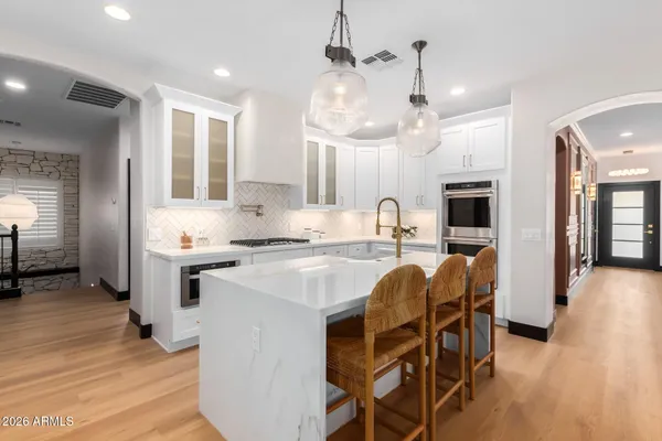 a large kitchen with kitchen island a stove a sink a center island and wooden floor