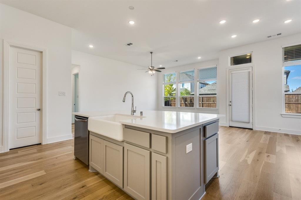 1704 Hydrangea Lane Prosper, TX 75078 - Photo 8 of 25 Kitchen with light wood finished floors, an island with sink, recessed lighting, ceiling fan, and light stone countertops