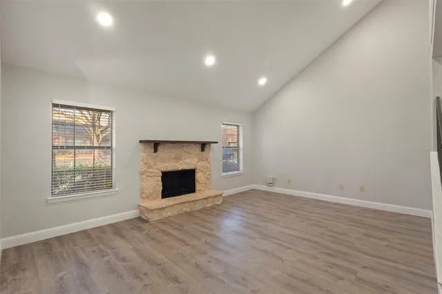 an empty room with wooden floor fireplace and windows