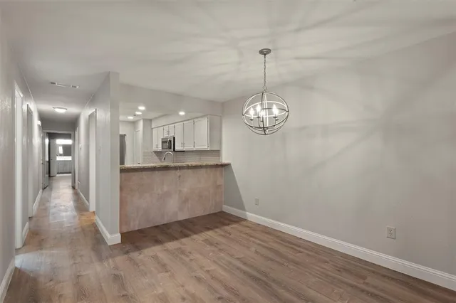 a view of a room with wooden floor and kitchen view