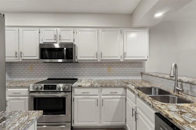 a kitchen with granite countertop white cabinets and a stove top oven