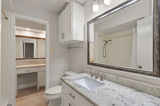 a bathroom with a granite countertop toilet a sink and a mirror