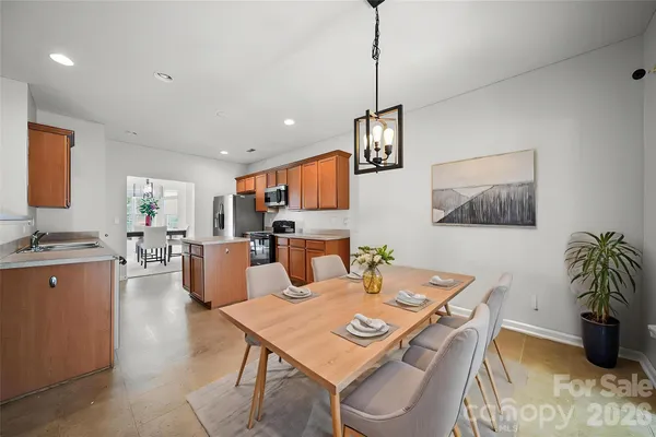 a view of a dining room and livingroom with furniture wooden floor a rug a painting and a chandelier