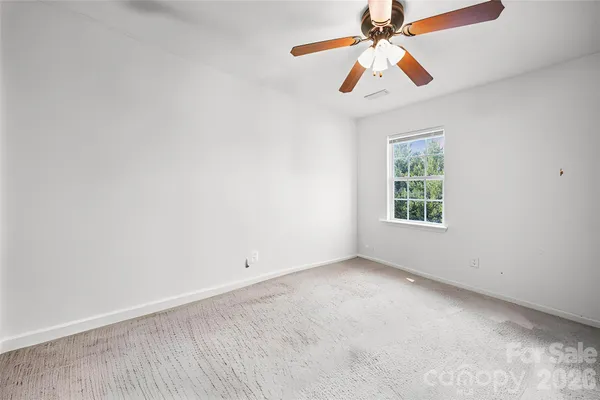 an empty room with a window and a fan