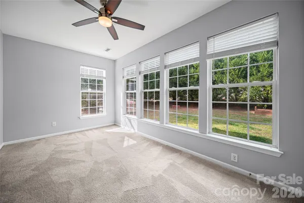 a view of an empty room with a window and ceiling fan