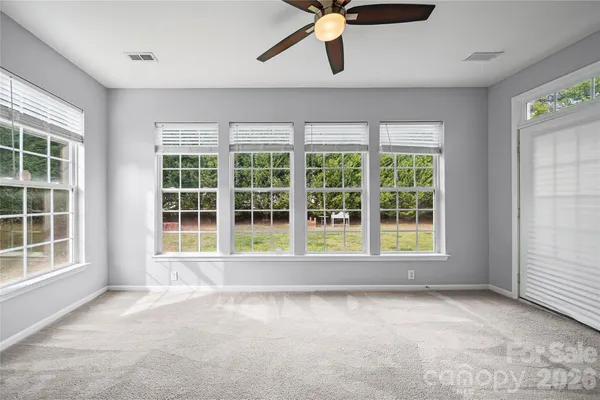a view of an empty room with a window and ceiling fan