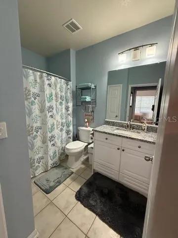 a bathroom with a granite countertop sink mirror vanity and toilet
