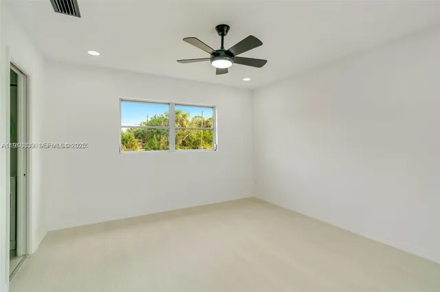 an empty room with ceiling fan and window