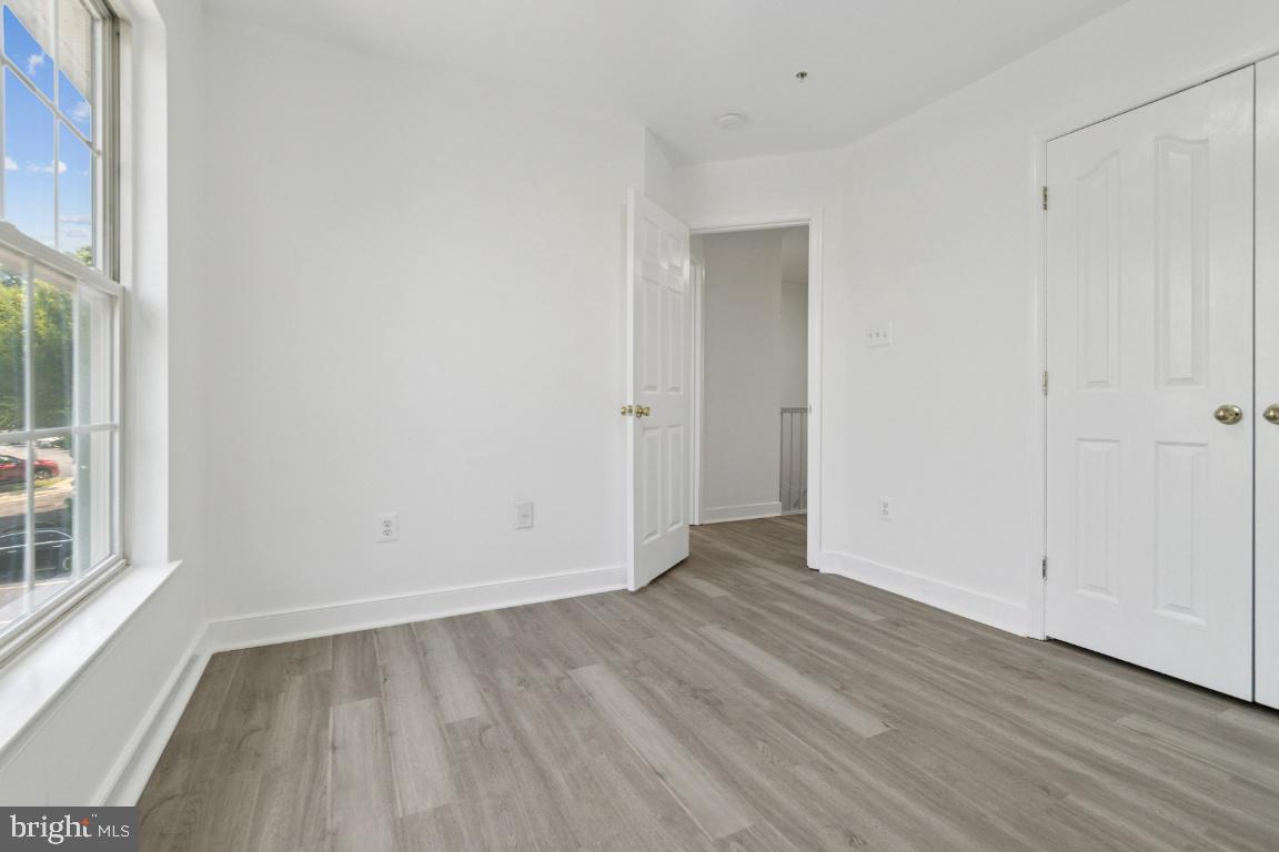 1109 Pomelo Court, Unit 1109 Baltimore, MD 21228 - Photo 24 of 40 a view of an empty room with wooden floor and a window