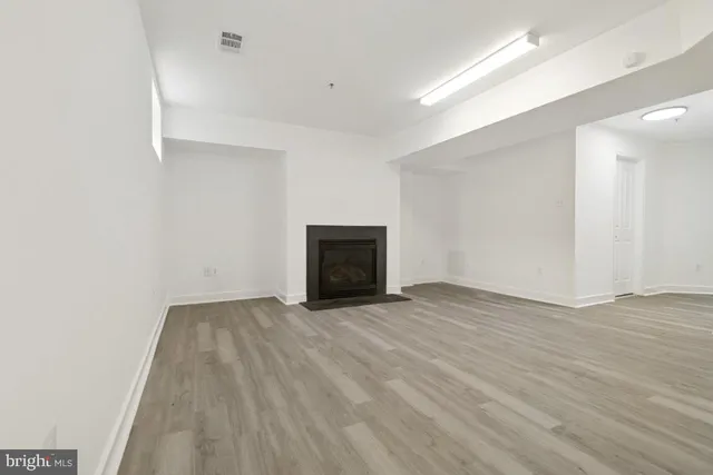 a view of an empty room with wooden floor and a fireplace