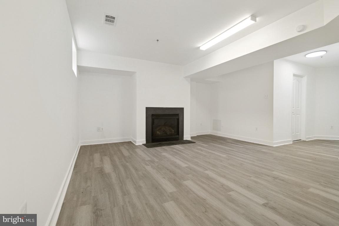 1109 Pomelo Court, Unit 1109 Baltimore, MD 21228 - Photo 36 of 40 a view of an empty room with wooden floor and a fireplace